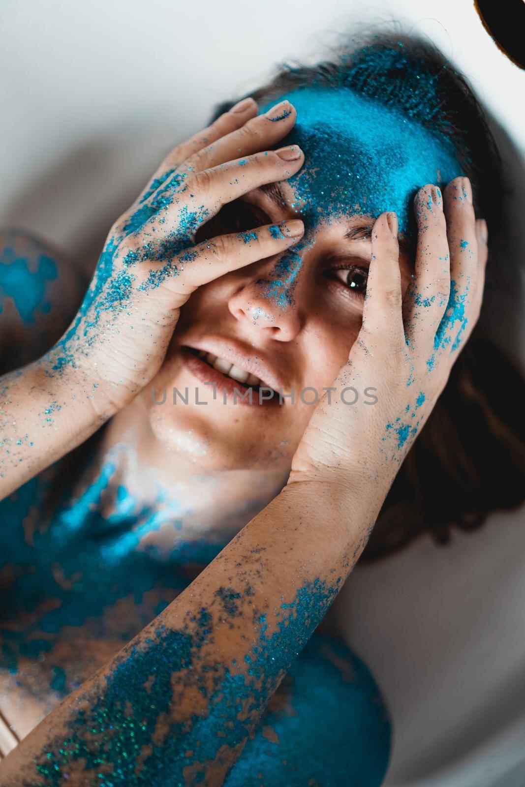 Portrait of beautiful woman with blue sparkles on her face in the bath. The concept of Individuality