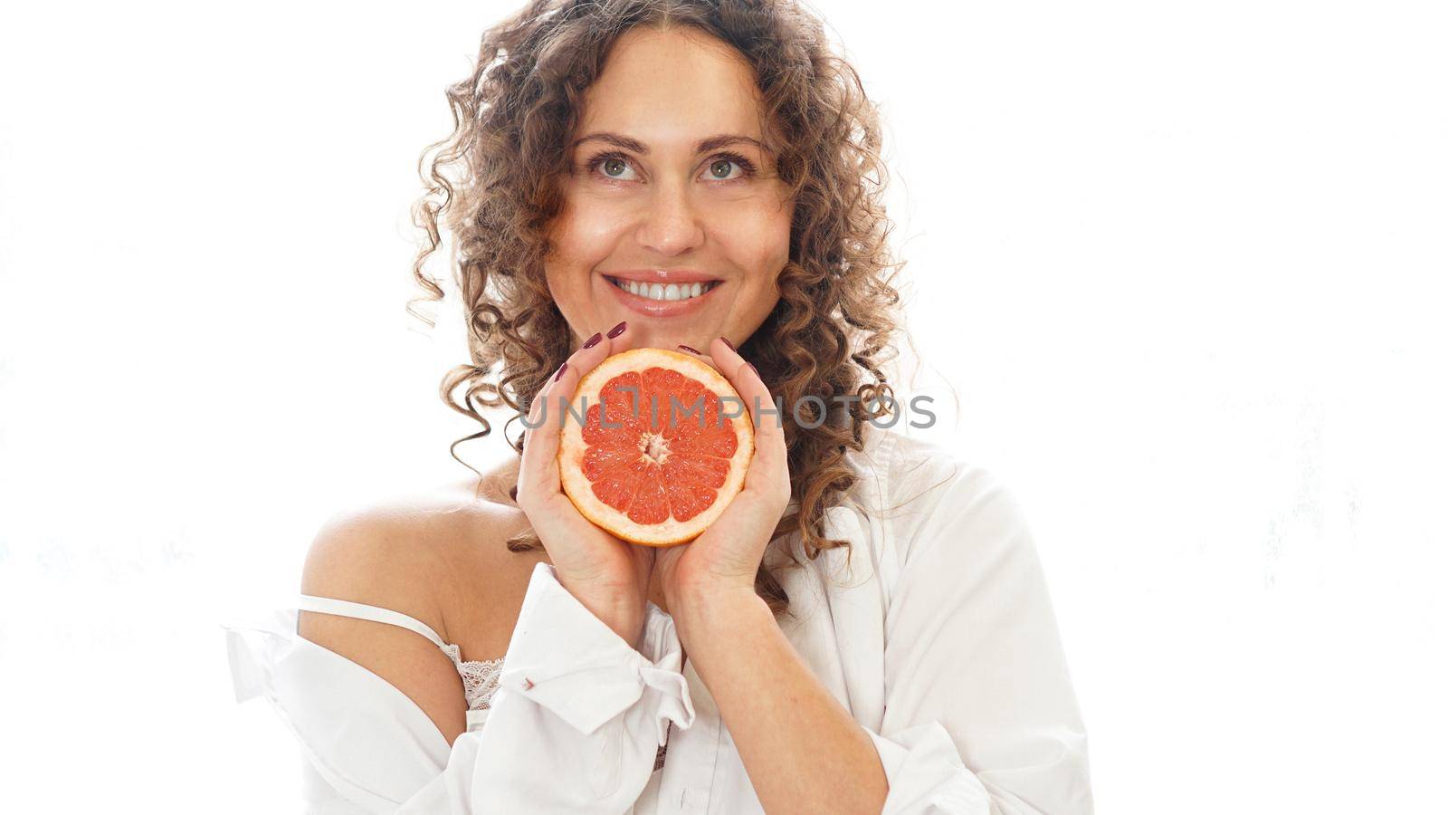 Portrait of pretty middle-aged woman with curly hair with grapefruit by natali_brill