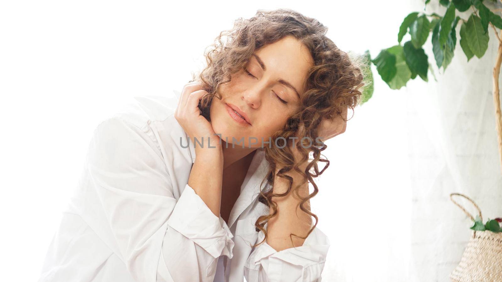 Portrait of a beautiful woman sitting at home with plants and smiling at camera. Happy morning - sunny day