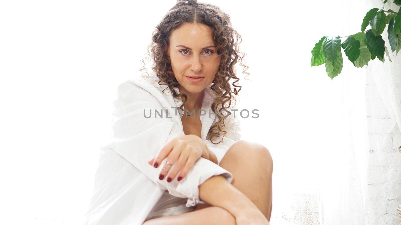 Portrait of a beautiful woman sitting at home with plants and smiling at camera. Happy morning - sunny day