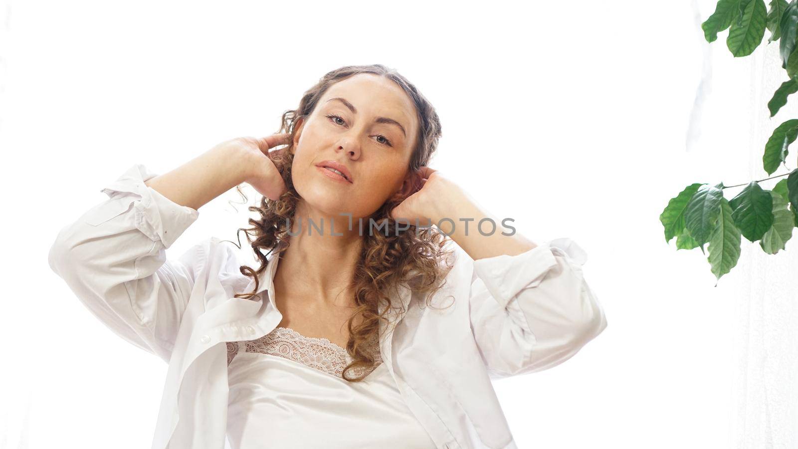 Portrait of a beautiful woman sitting at home with plants and smiling at camera. Happy morning - sunny day