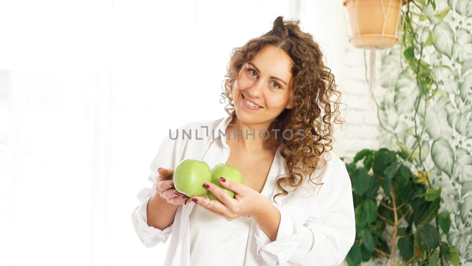 Senior happy woman with curly hair with green apples. Diet. Healthy lifestyle.