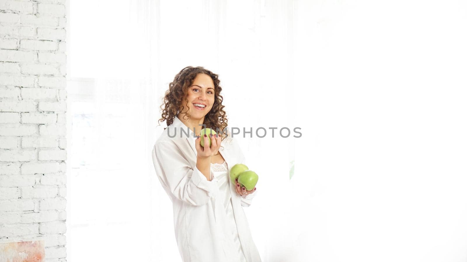 Senior happy woman with curly hair with green apples. Diet. Healthy lifestyle.