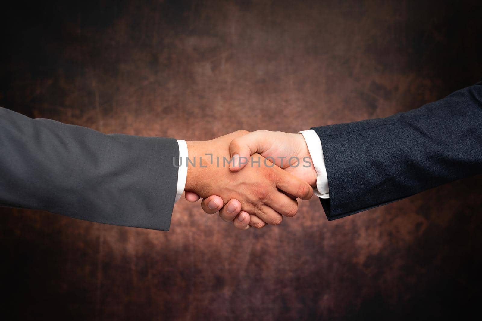 Corporate Businessmen Handshake Indoors.Two People Professionally Well Dressed Gesturing Togetherness.Working Colleague Partners Sign Deal In Agreement To Contract by nialowwa