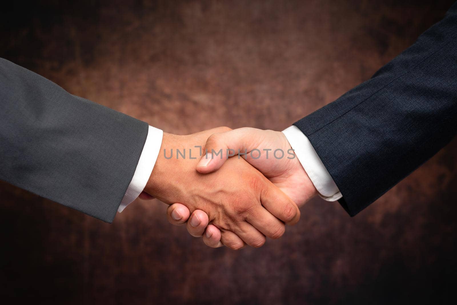 Corporate Businessmen Handshake Indoors.Two People Professionally Well Dressed Gesturing Togetherness.Working Colleague Partners Sign Deal In Agreement To Contract by nialowwa