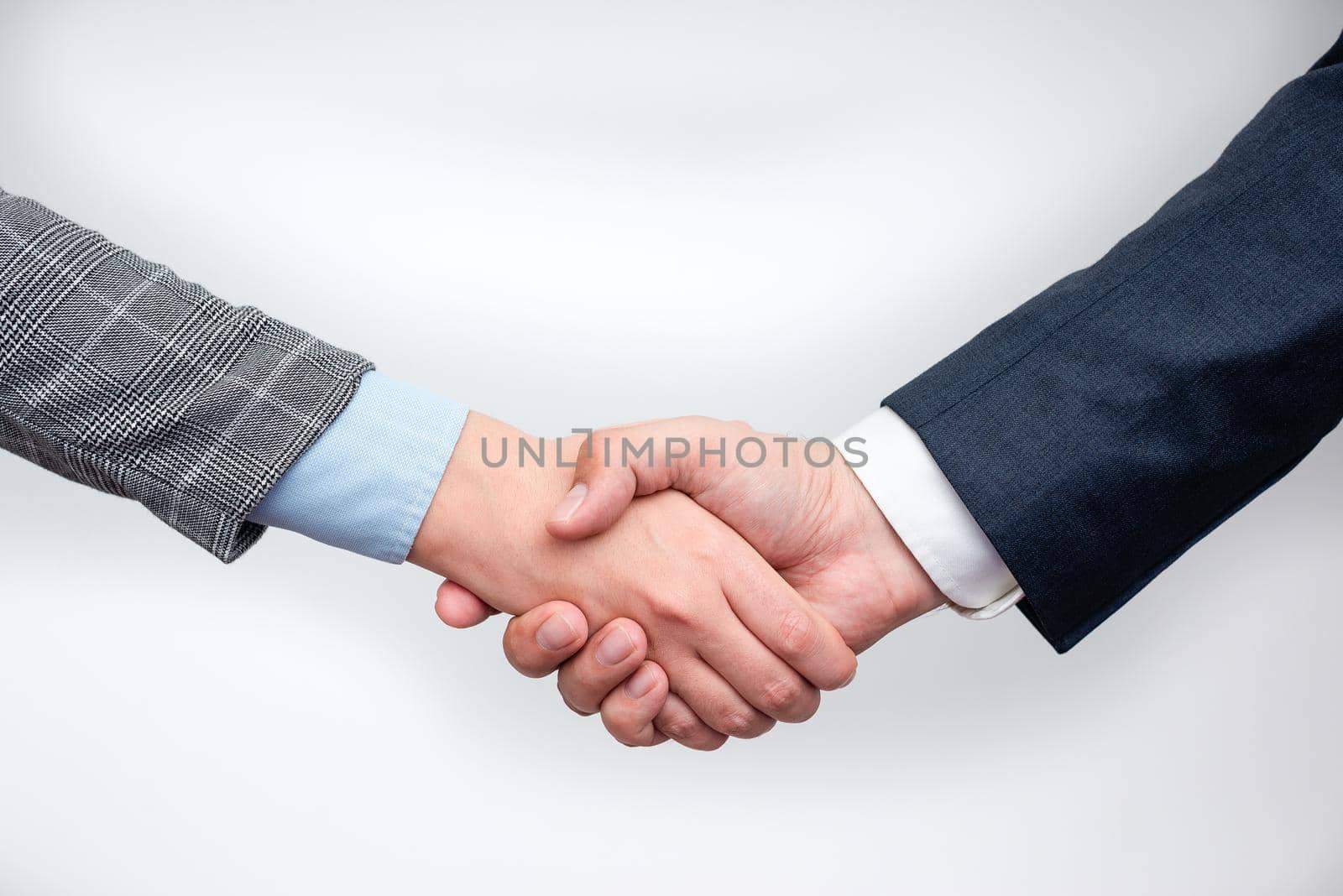 Corporate Businessmen Handshake Indoors.Two People Professionally Well Dressed Gesturing Togetherness.Working Colleague Partners Sign Deal In Agreement To Contract by nialowwa