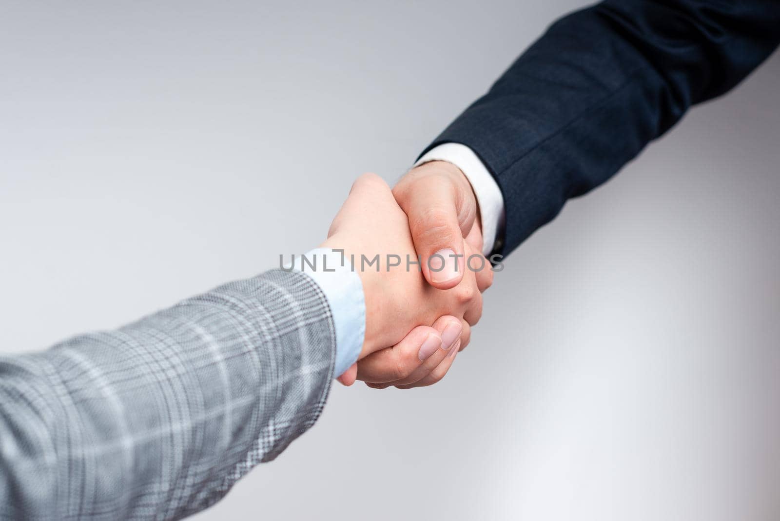 Corporate Businessmen Handshake Indoors.Two People Professionally Well Dressed Gesturing Togetherness.Working Colleague Partners Sign Deal In Agreement To Contract by nialowwa
