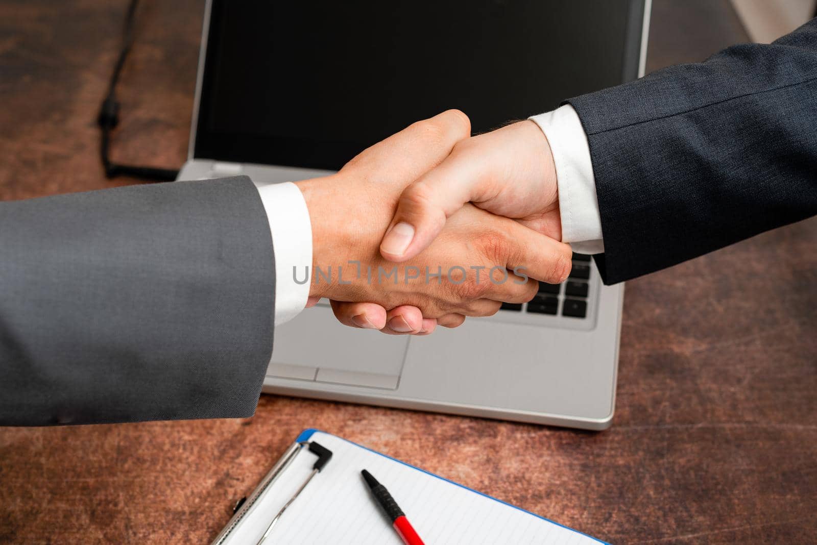 Corporate Businessmen Handshake Indoors.Two People Professionally Well Dressed Gesturing Togetherness.Working Colleague Partners Sign Deal In Agreement To Contract by nialowwa