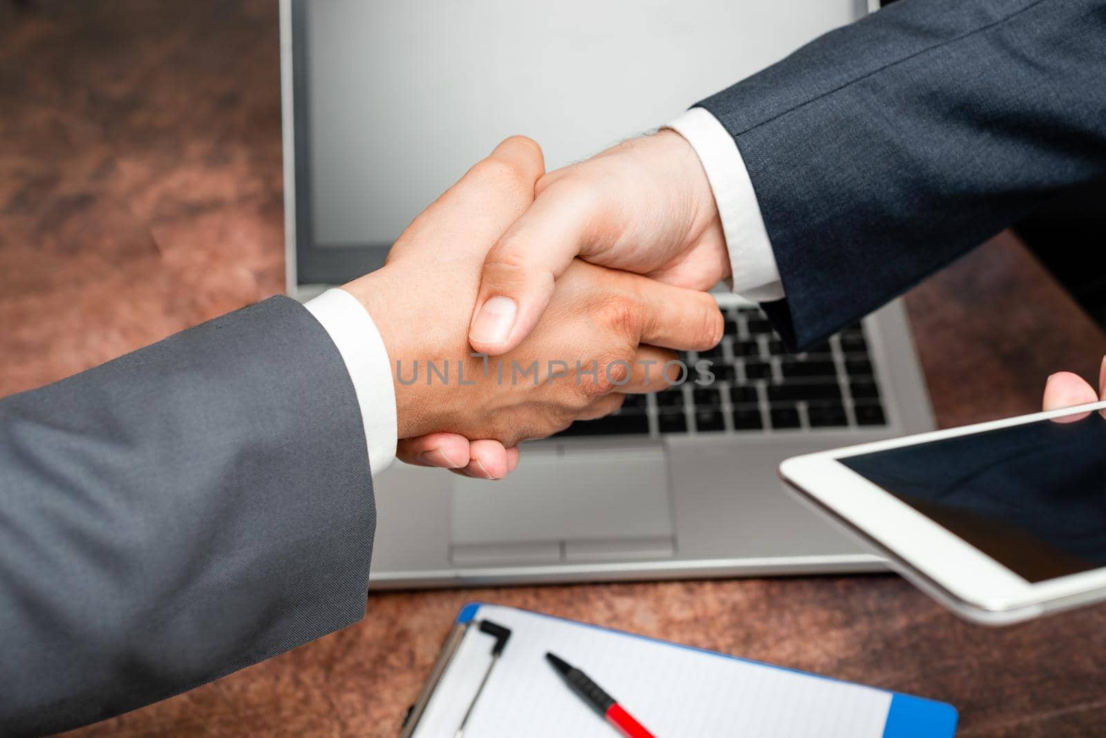 Corporate Businessmen Handshake Indoors.Two People Professionally Well Dressed Gesturing Togetherness.Working Colleague Partners Sign Deal In Agreement To Contract by nialowwa