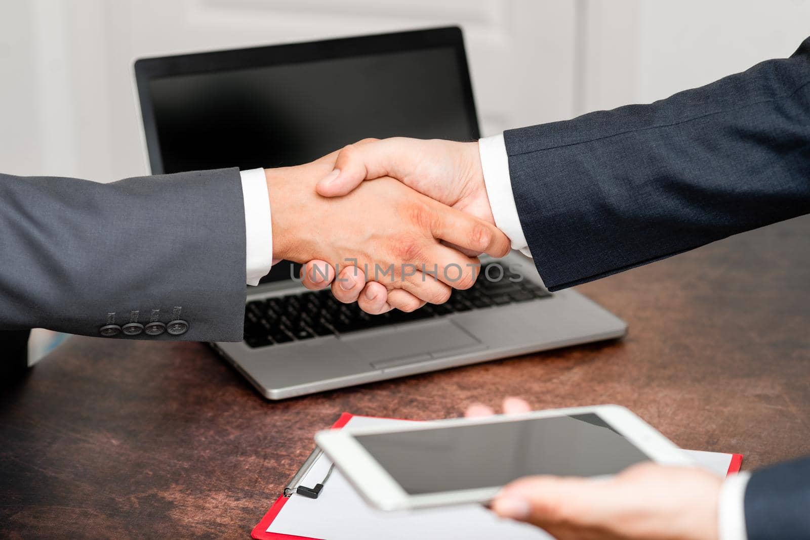 Corporate Businessmen Handshake Indoors.Two People Professionally Well Dressed Gesturing Togetherness.Working Colleague Partners Sign Deal In Agreement To Contract by nialowwa