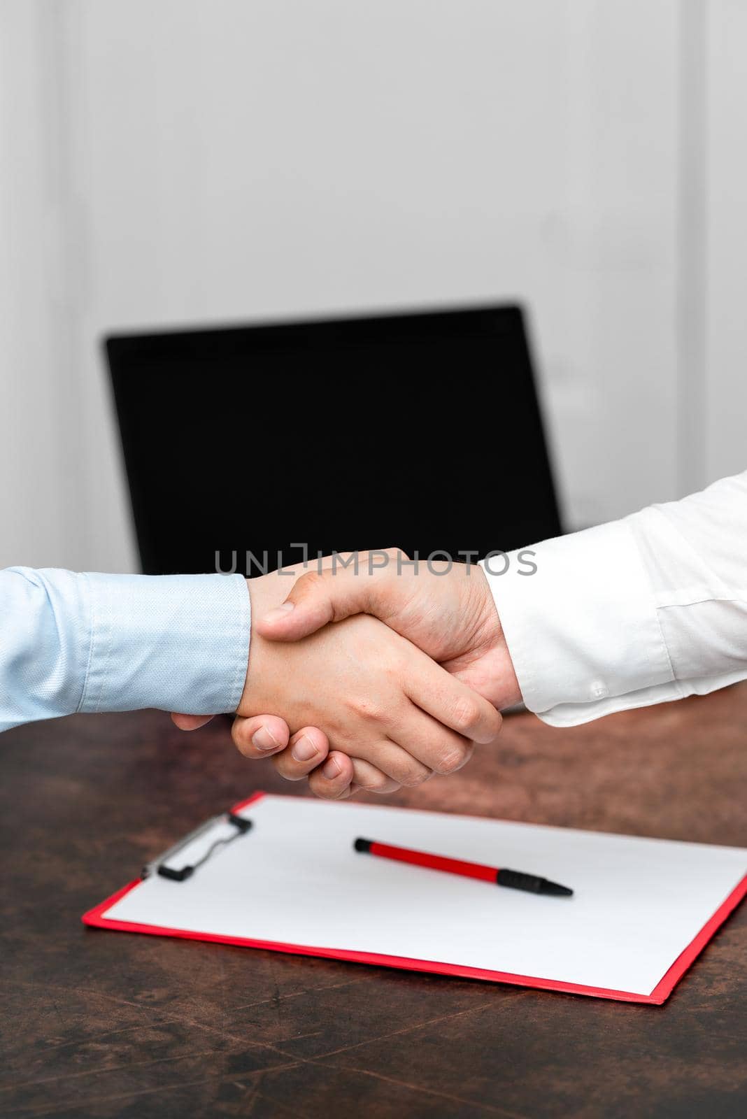 Corporate Businessmen Handshake Indoors.Two People Professionally Well Dressed Gesturing Togetherness.Working Colleague Partners Sign Deal In Agreement To Contract by nialowwa