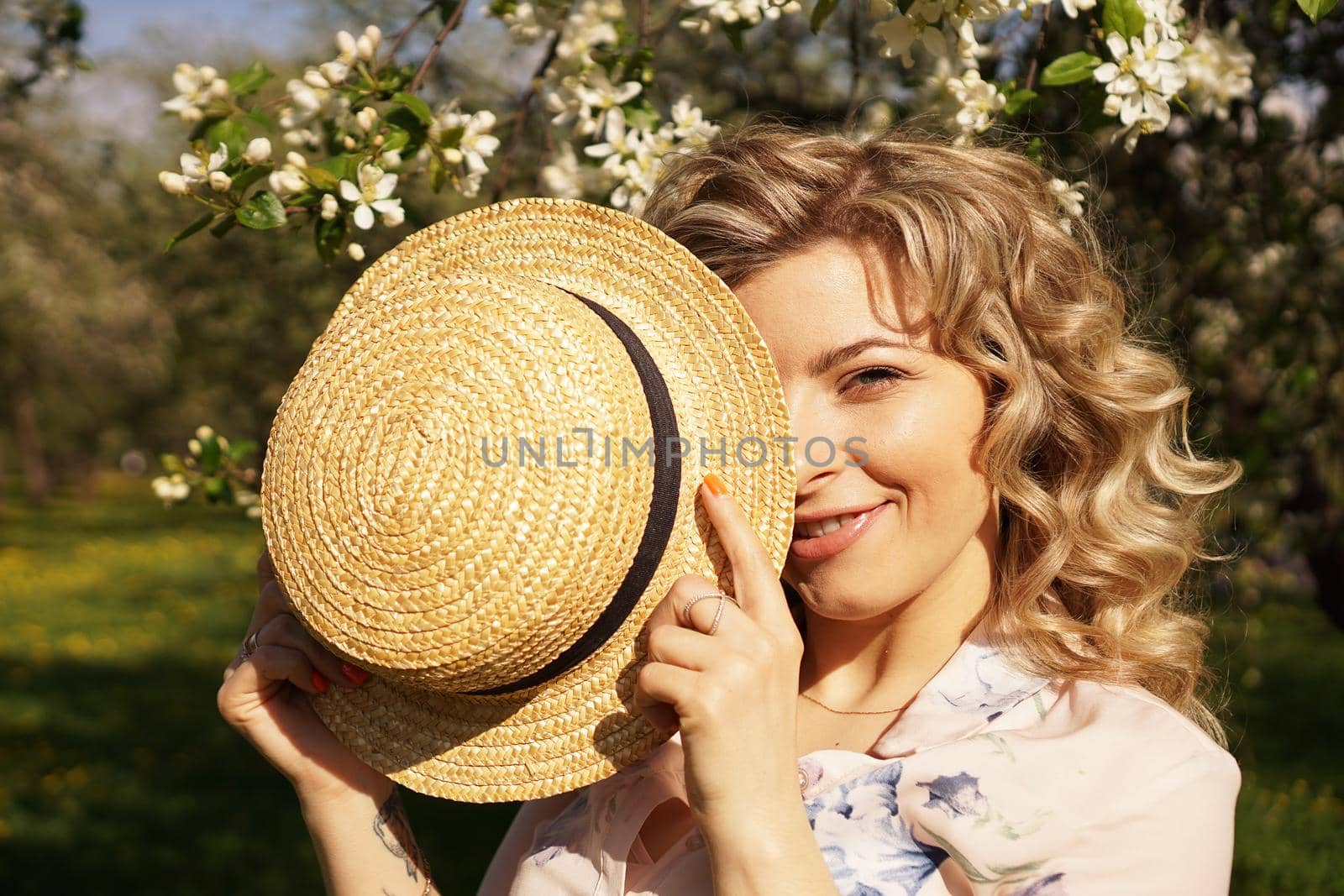 Woman covered half the face with a straw hat - happy time in the green garden by natali_brill