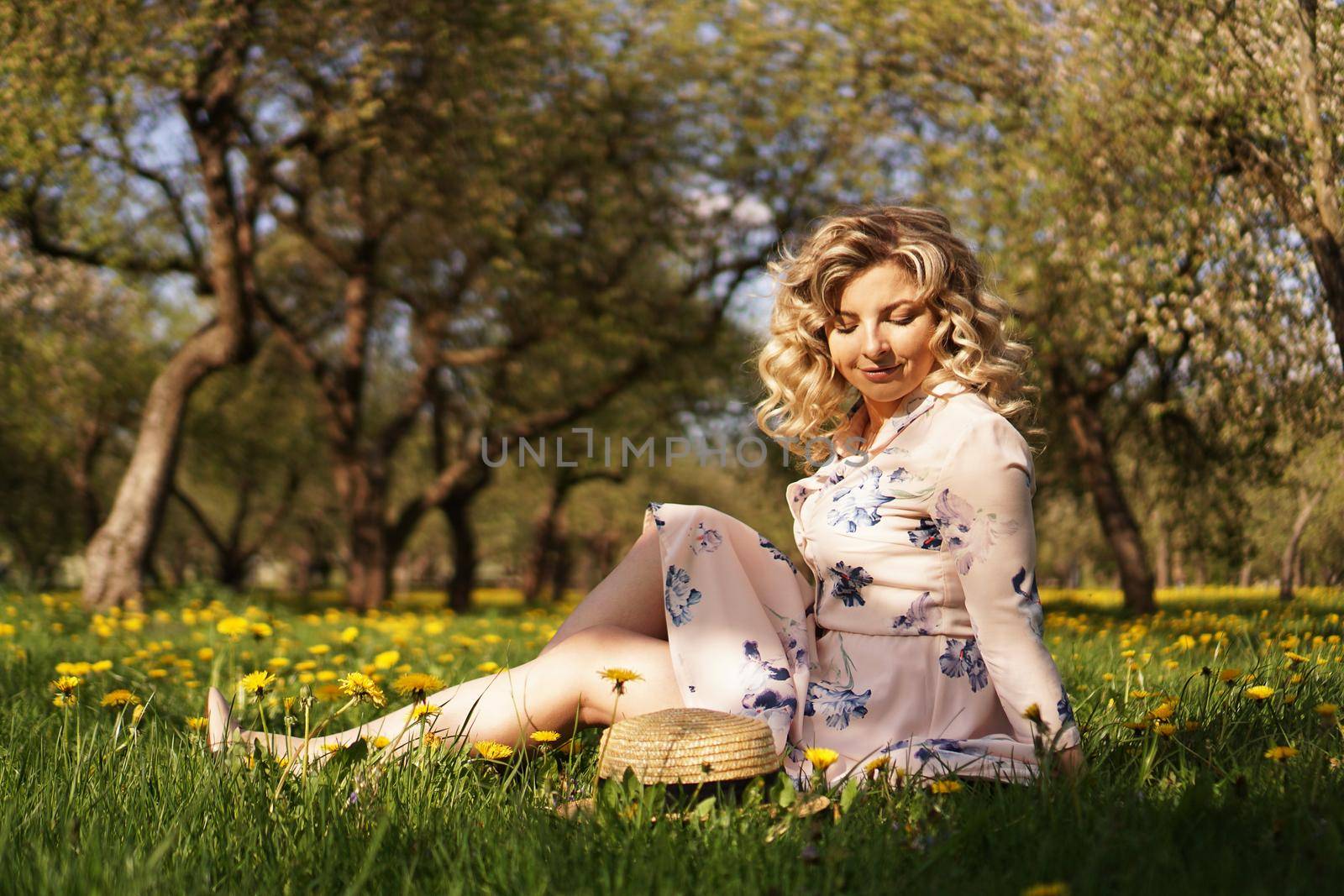 Cute woman rest in the green summer park with dandelions