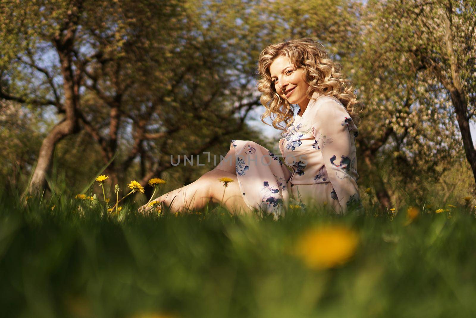 Cute woman rest in the green summer park with dandelions