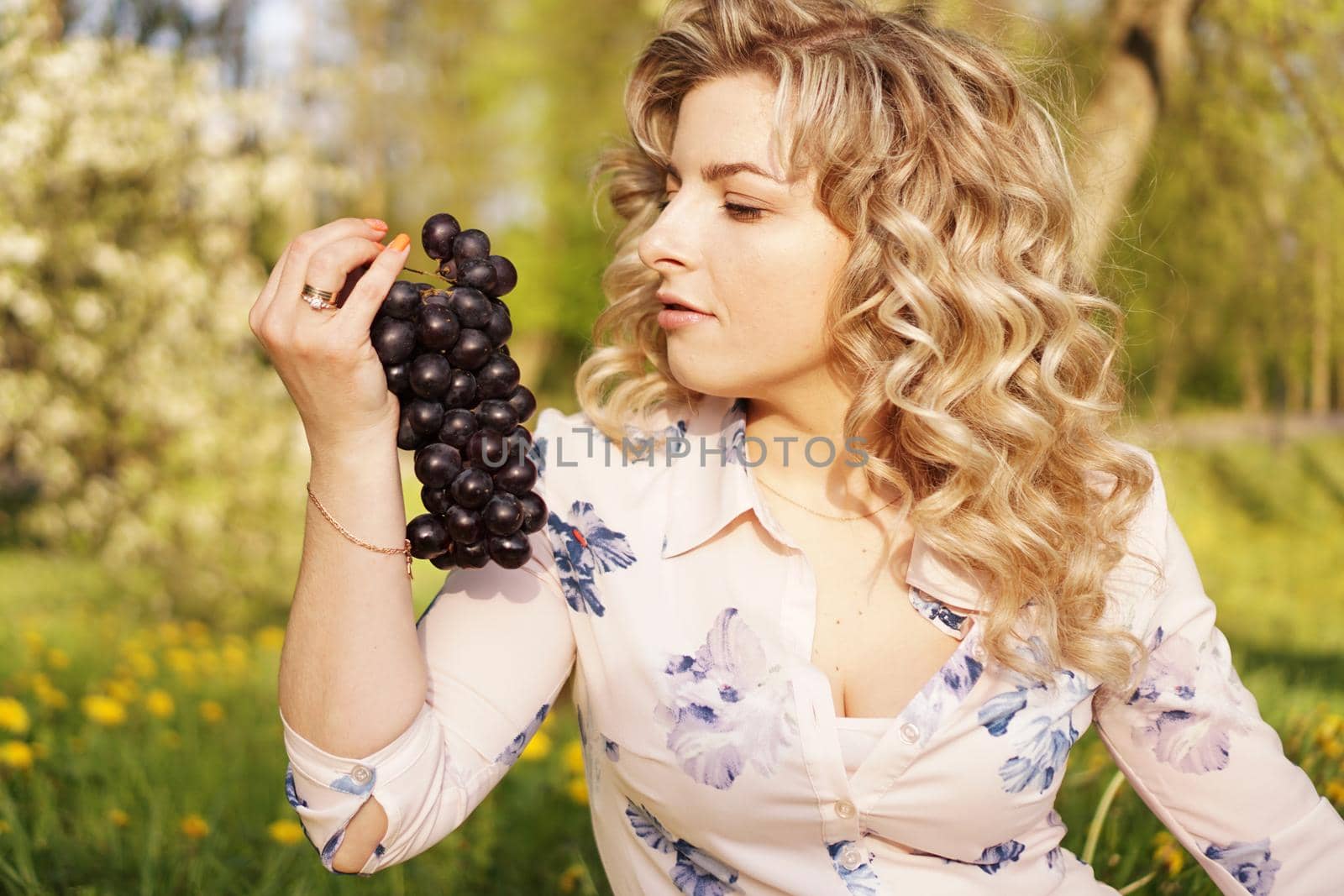 Happy woman with grape at a picnic in summer garden