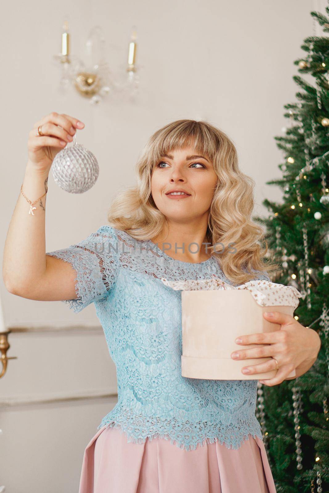 Young woman decorates Christmas tree with Christmas toys by natali_brill