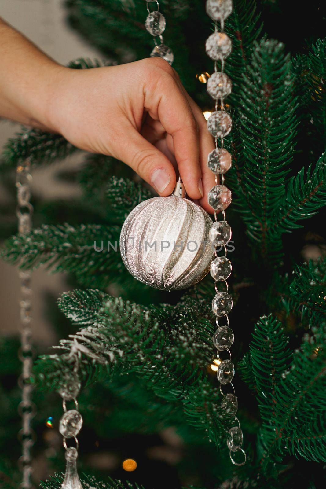 Female hand decorating christmas tree with a silver balls. by natali_brill