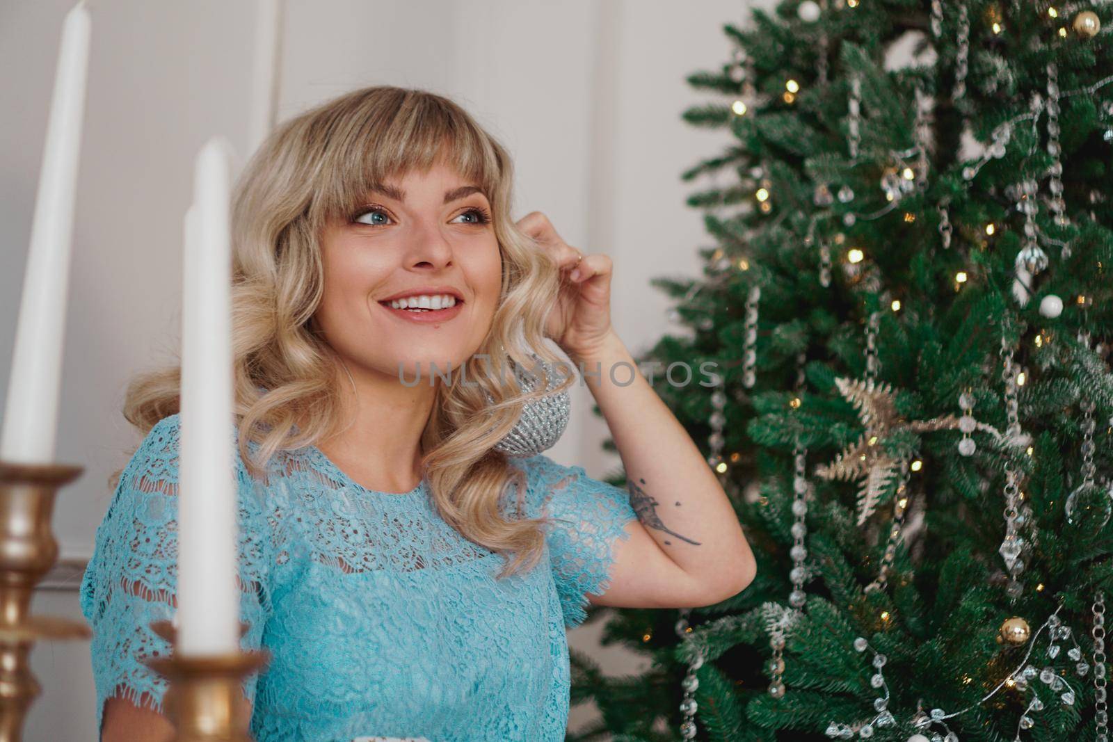 Young woman decorates Christmas tree with Christmas toys by natali_brill