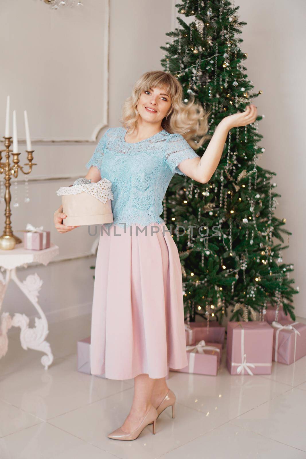 Young woman decorates Christmas tree with Christmas toys by natali_brill