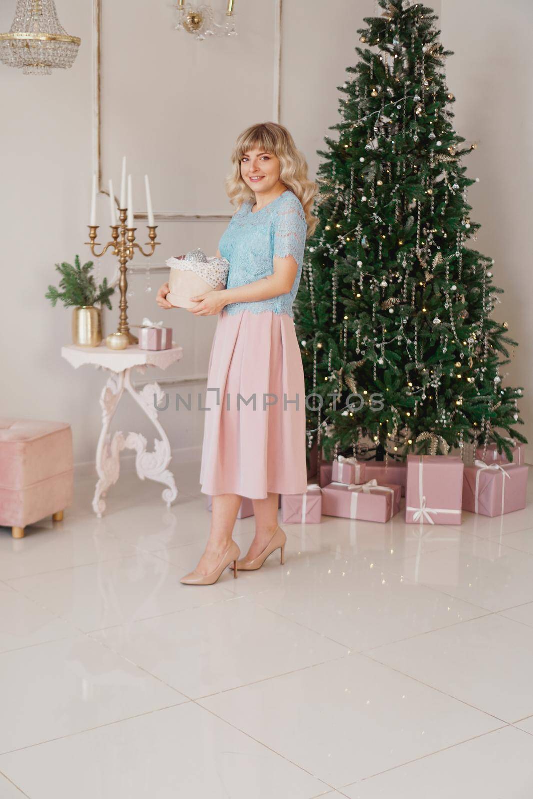 Young woman decorates Christmas tree with Christmas toys by natali_brill