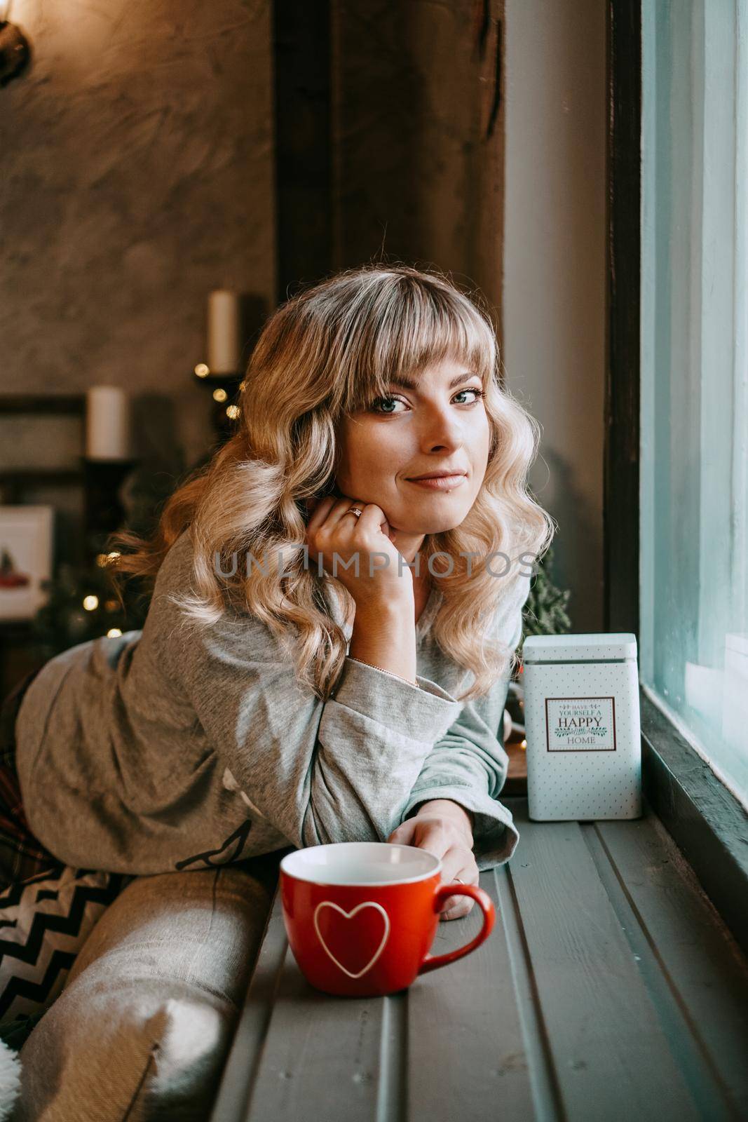 Young woman in plaid with cup of hot tea in a Christmas cozy interior. The concept of preparation for the holidays, Make a wish and dream