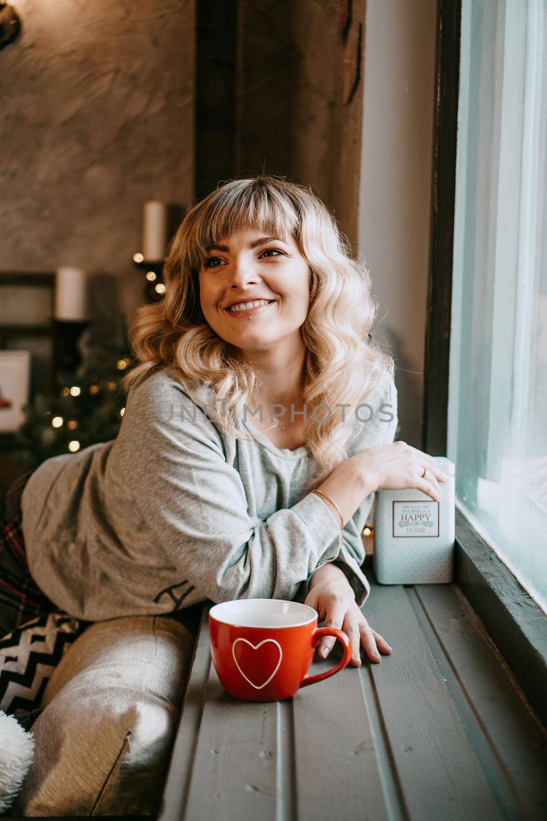 Young woman in plaid with cup of hot tea in a Christmas cozy interior. The concept of preparation for the holidays, Make a wish and dream