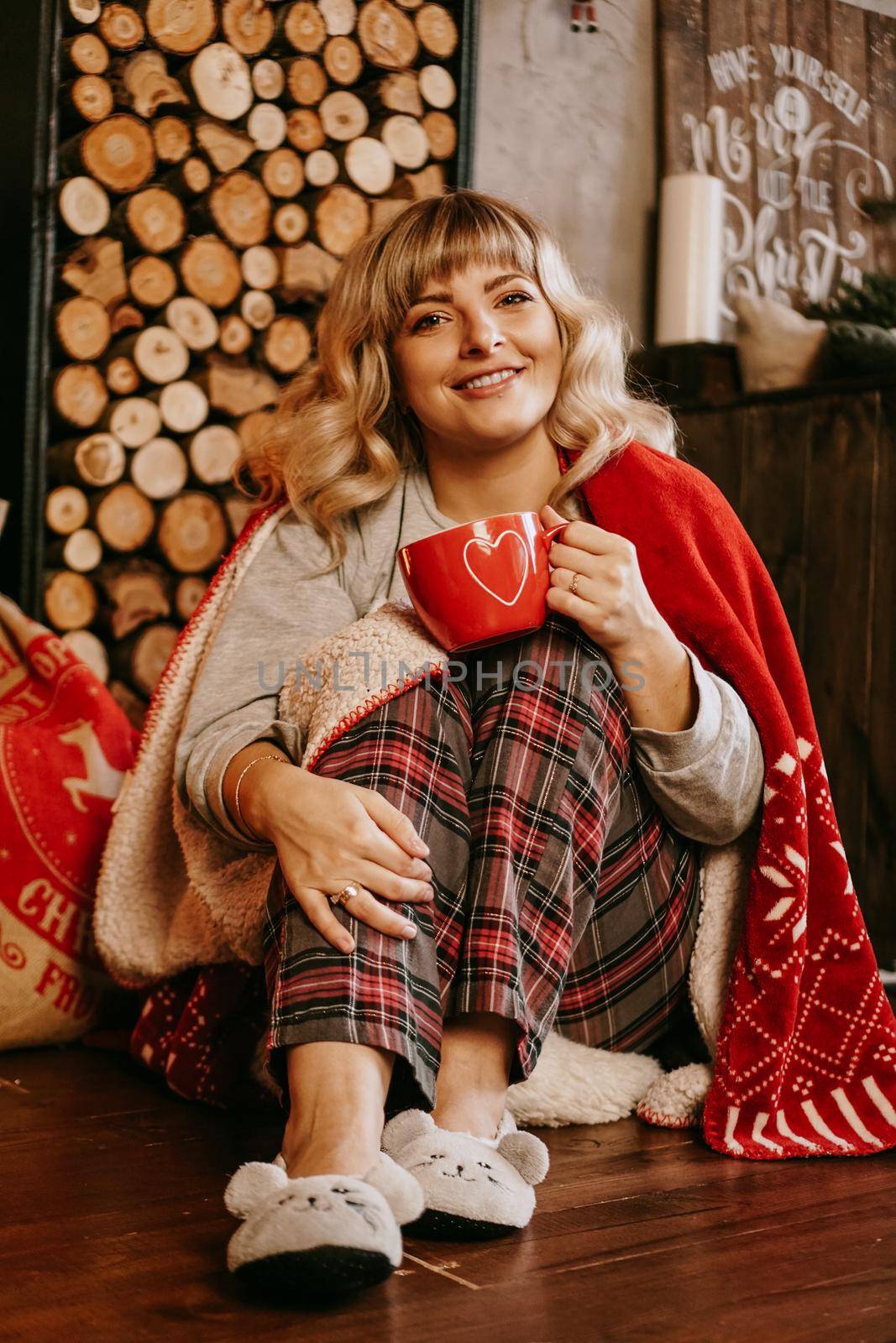 Young woman in plaid with cup of hot tea in a Christmas cozy interior. The concept of preparation for the holidays, Make a wish and dream