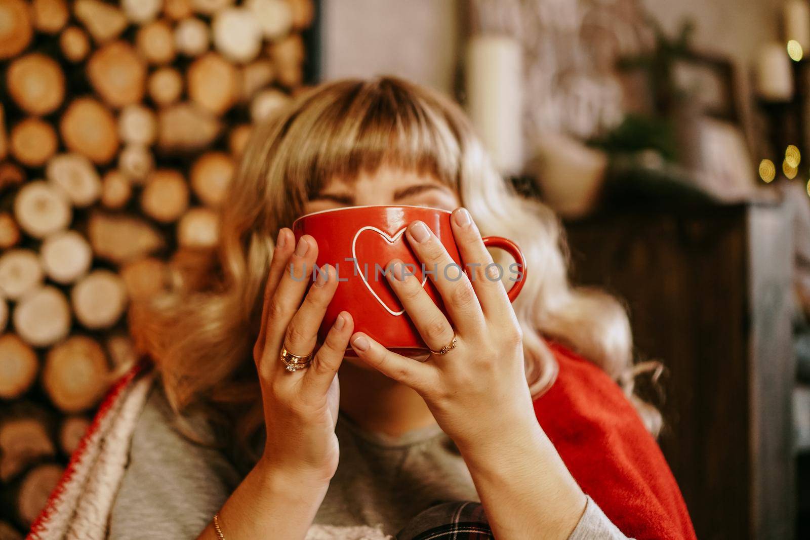 Young woman in plaid with cup of hot tea in a Christmas cozy interior. The concept of preparation for the holidays, Make a wish and dream