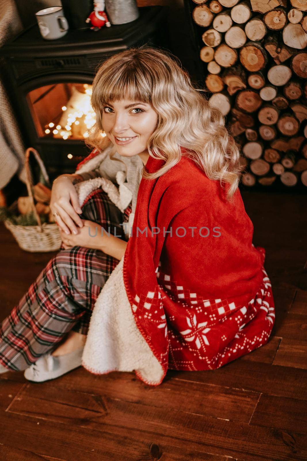 A beautiful young woman in a red plaid sits in a warm classic New Year interior