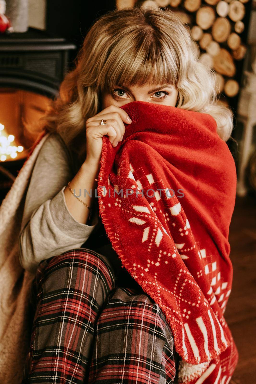 A beautiful young woman in a red plaid sits in a warm classic New Year interior