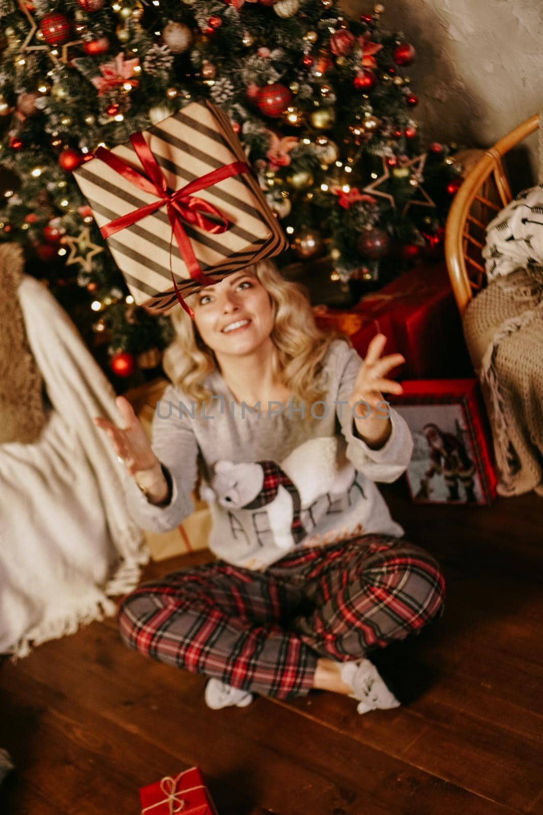 Woman throwing up a gift, concept of the new year, Christmas cozy interior