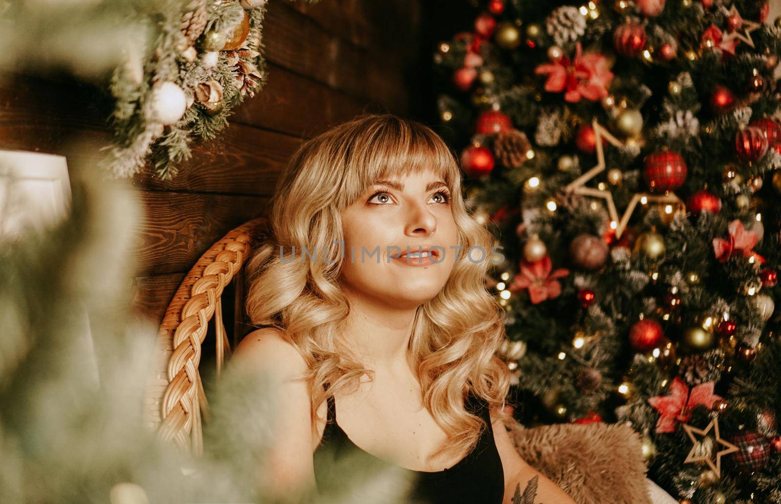 Close up portrait of beautiful young girl with long curly hair on a christmas background with lights. Magic warm new year photo. Cozy interior.