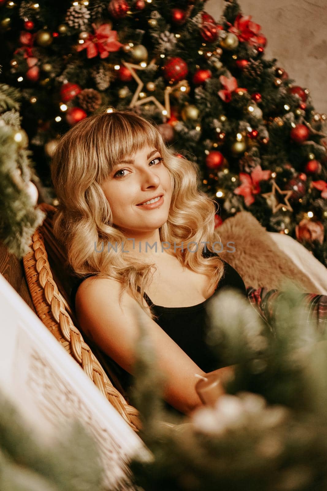 Close up portrait of beautiful young girl with long curly hair on a christmas background with lights. Magic warm new year photo. Cozy interior.