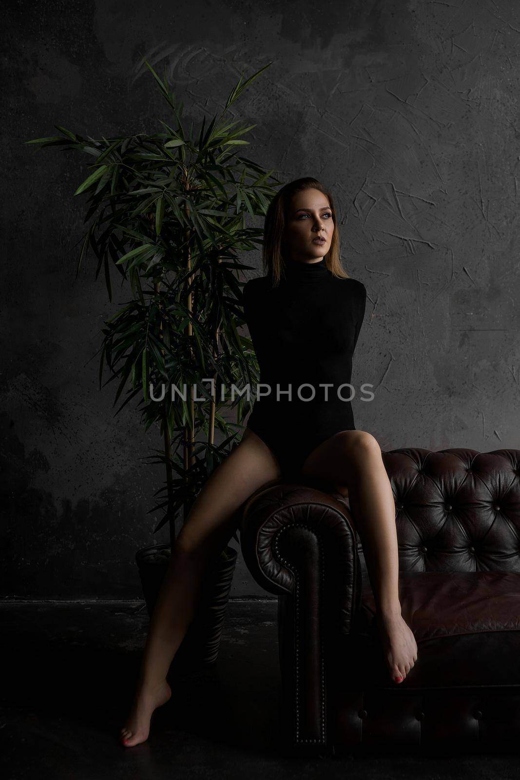 Beautiful sexy woman on leather sofa in dark room