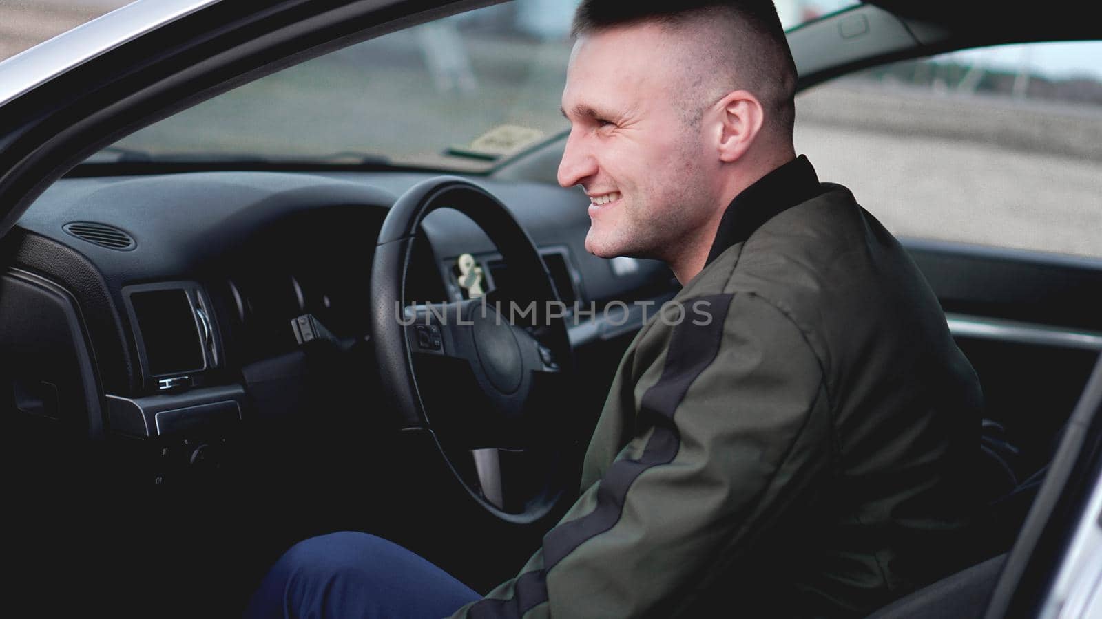 Attractive smiling young man in a car by natali_brill