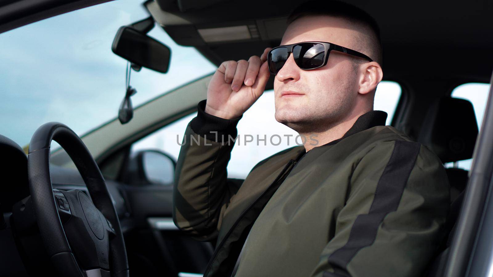 Side view of confident young stylish man in sunglasses in his car by natali_brill