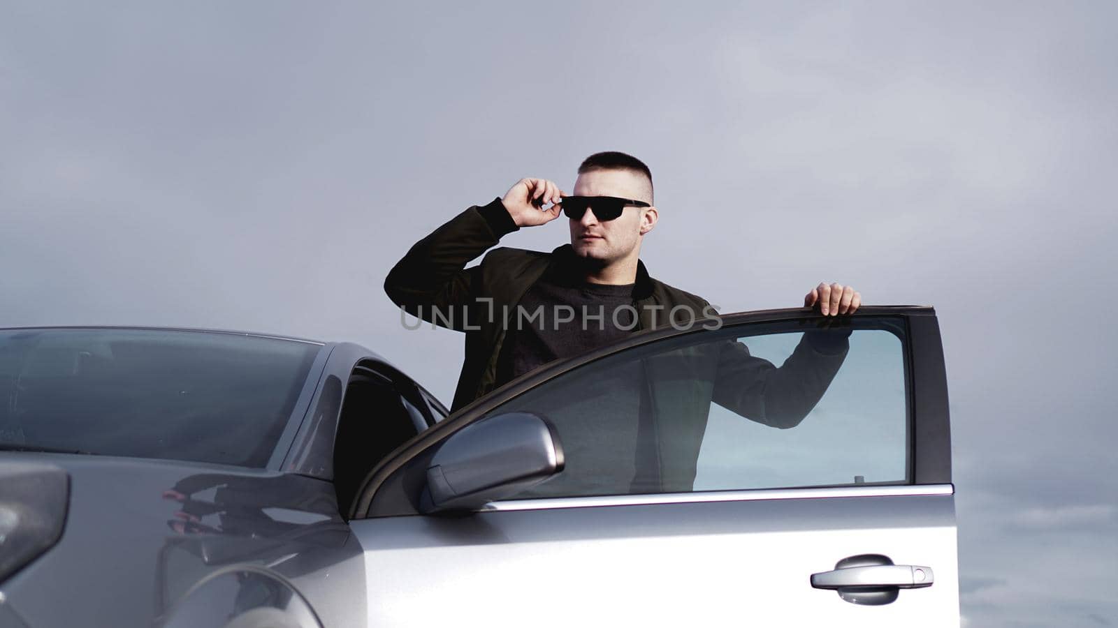 Handsome man in sunglasses near the car. Luxury life.