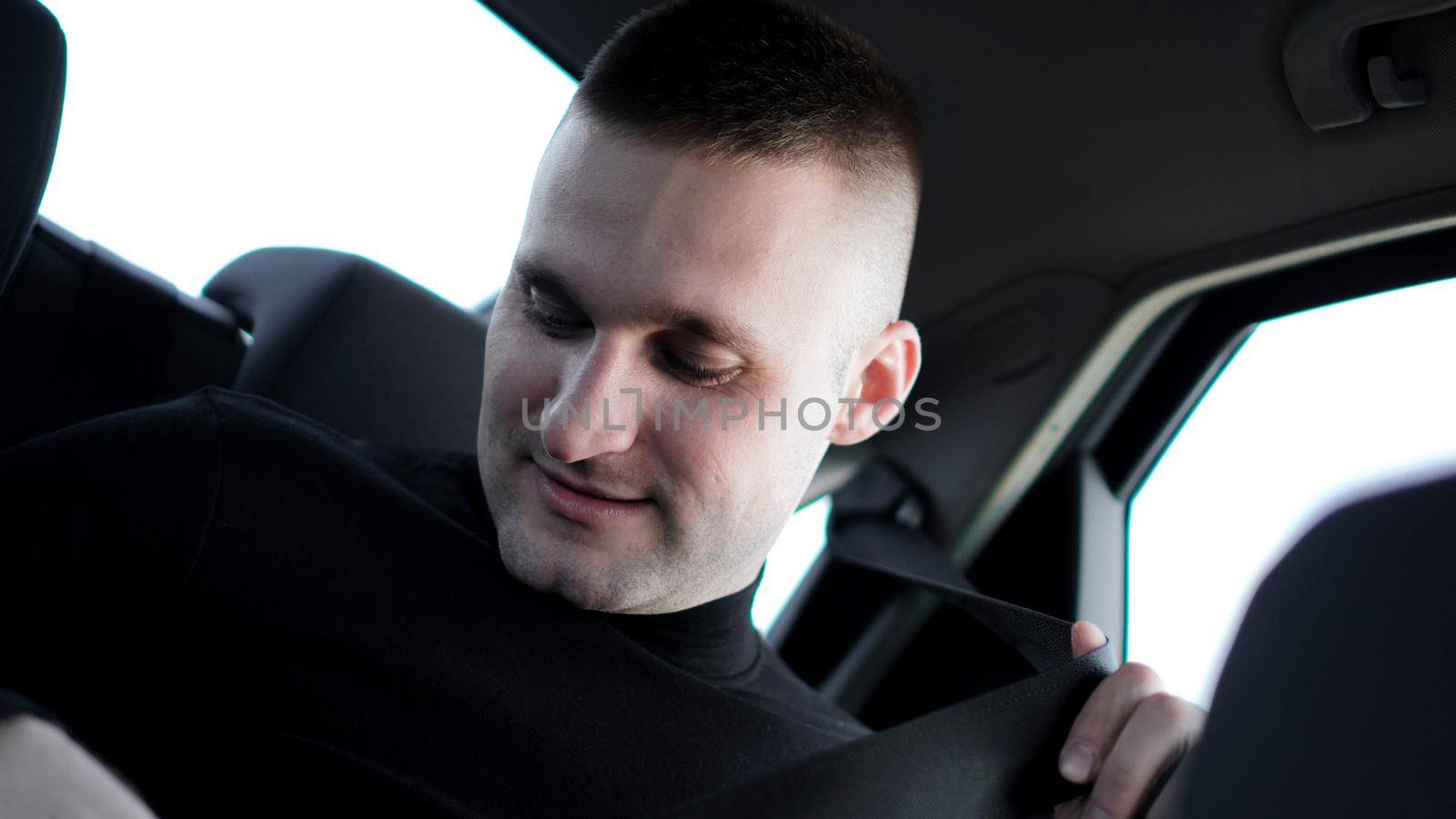 Confident young stylish Businessman in his car fastening the seatbelt, safe driving concept