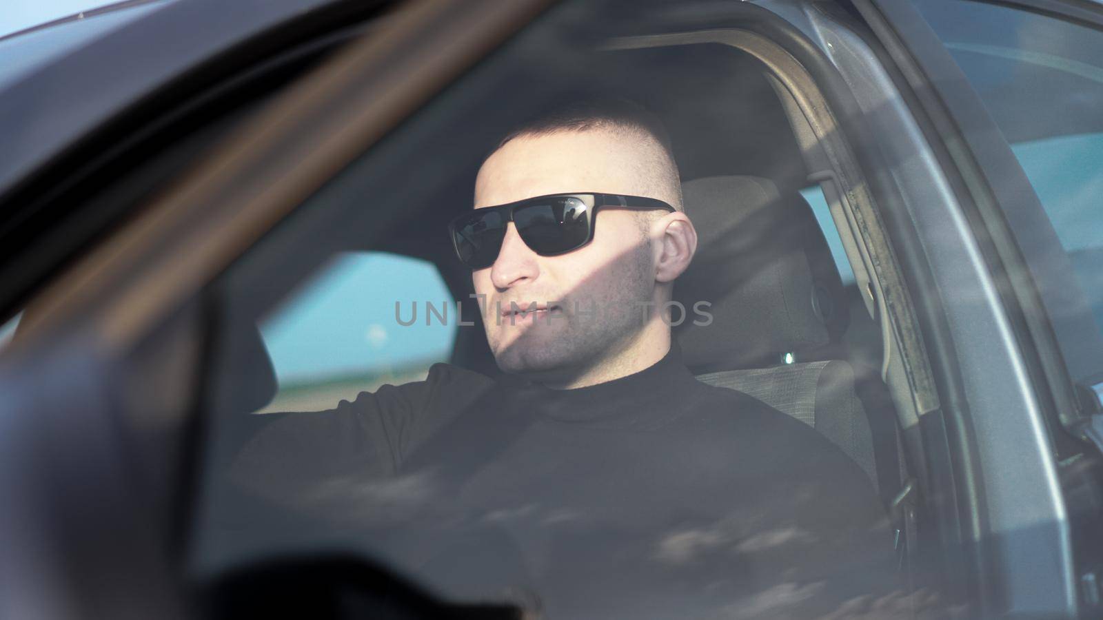 Side view of confident young stylish man in sunglasses in his car by natali_brill