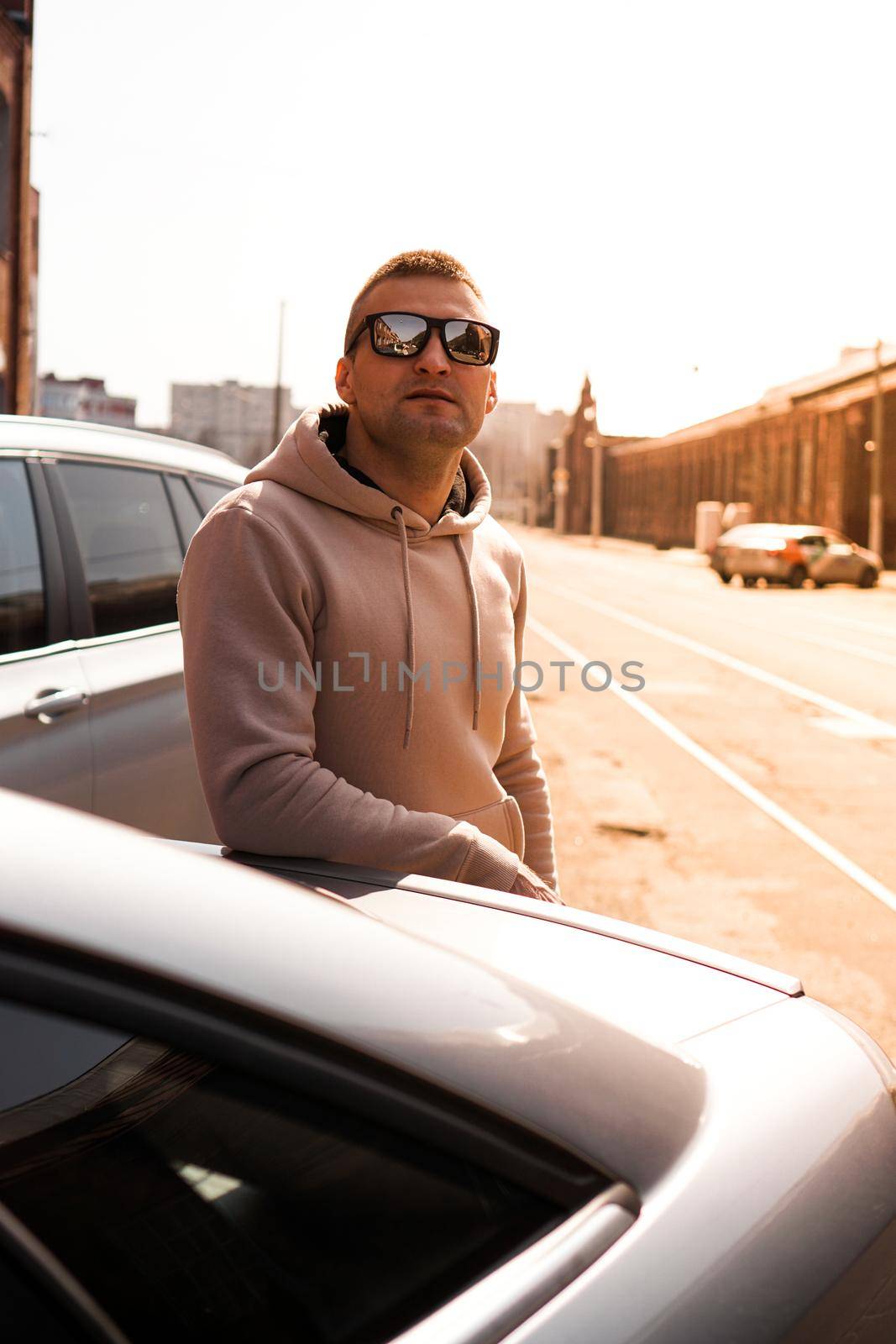 A young man next to his car on a sunny day on the street of the old city. by natali_brill