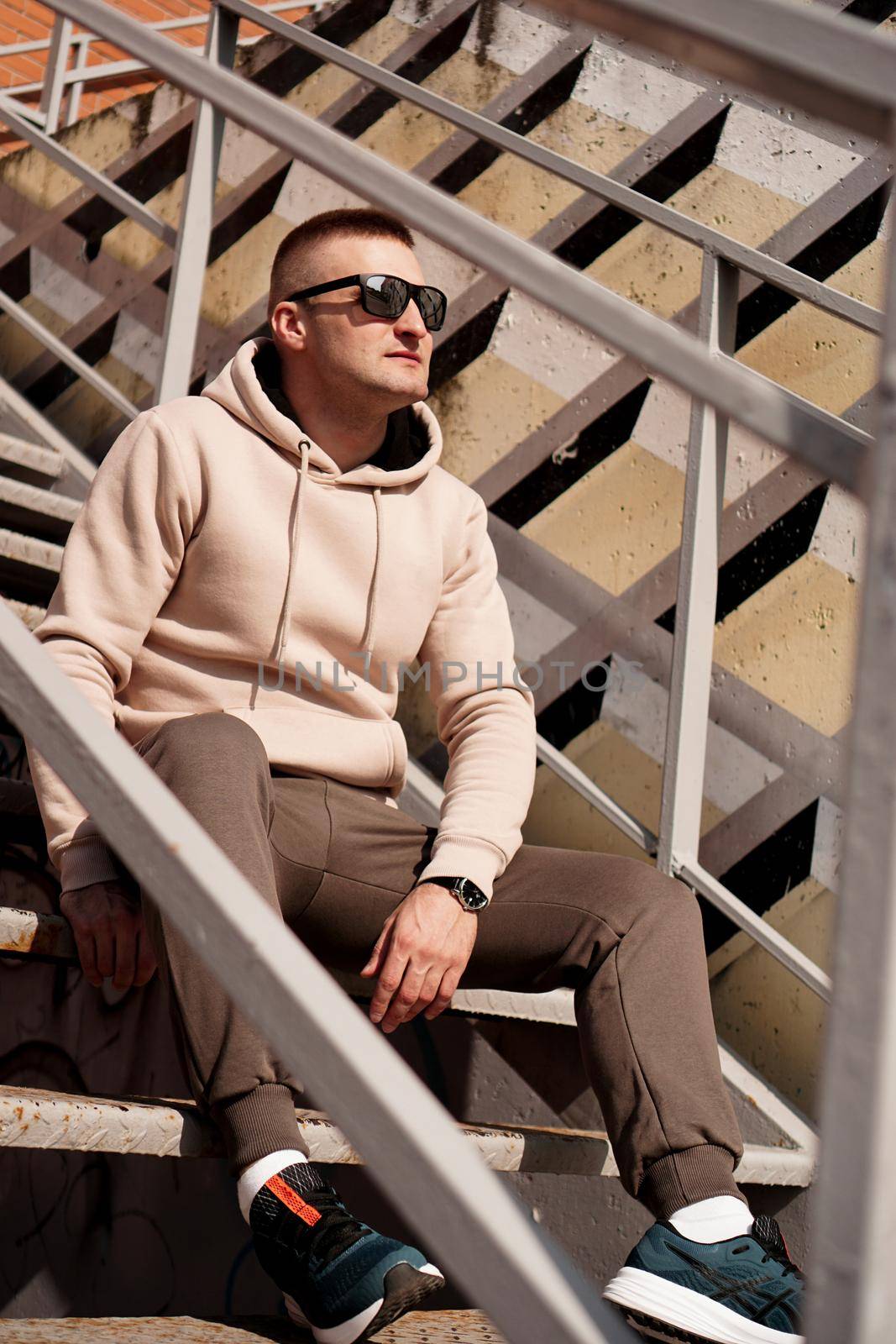 A young man sits on the steps in the city. Urban style. Lifestyle photo by natali_brill
