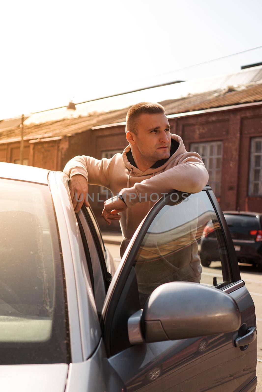 A young man next to his car on a sunny day on the street of the old city. by natali_brill