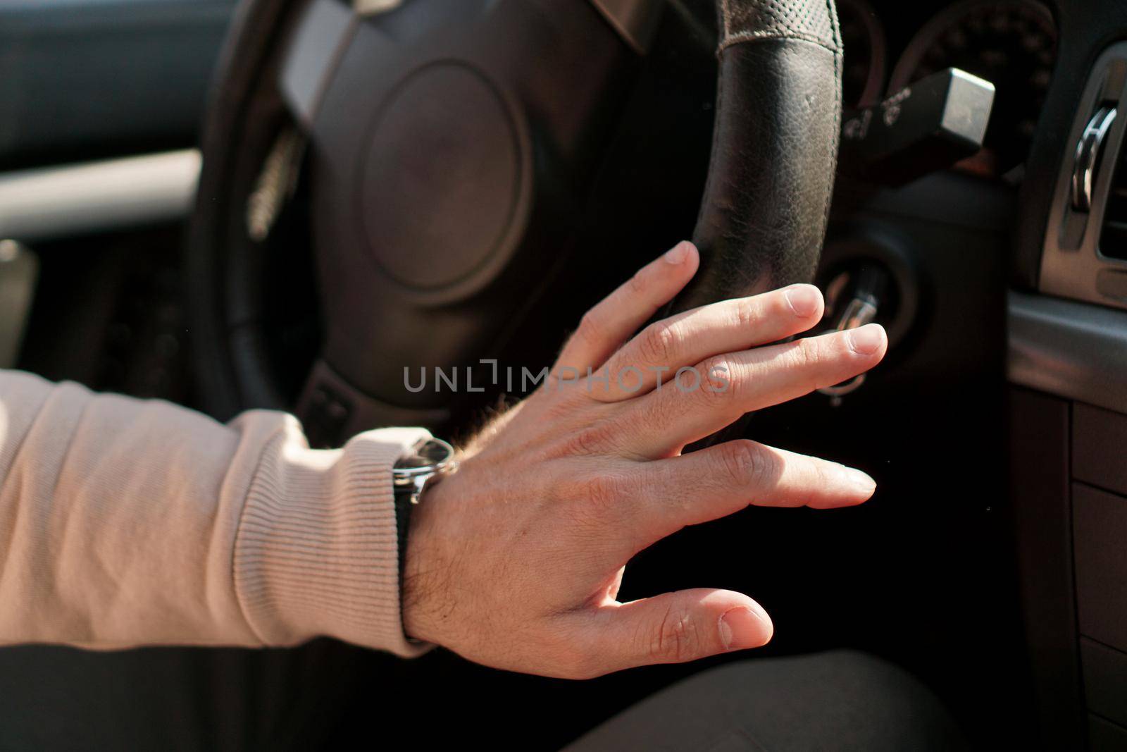 A man's hand on a steering wheel. Shabby steering wheel trim in a car. Watch on hand