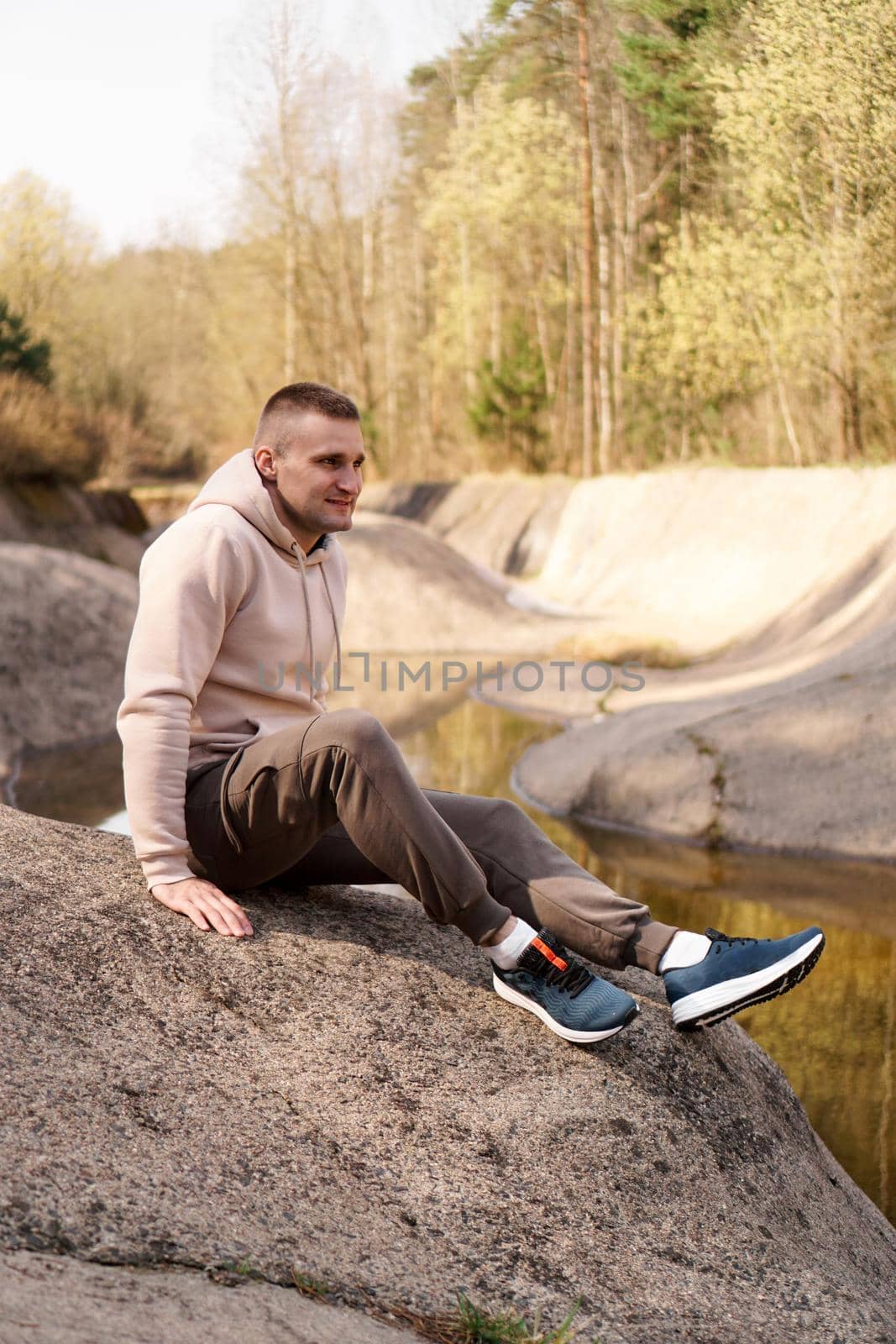 Young man in a comfortable suit at the edge of a rowing canal or mountain river by natali_brill