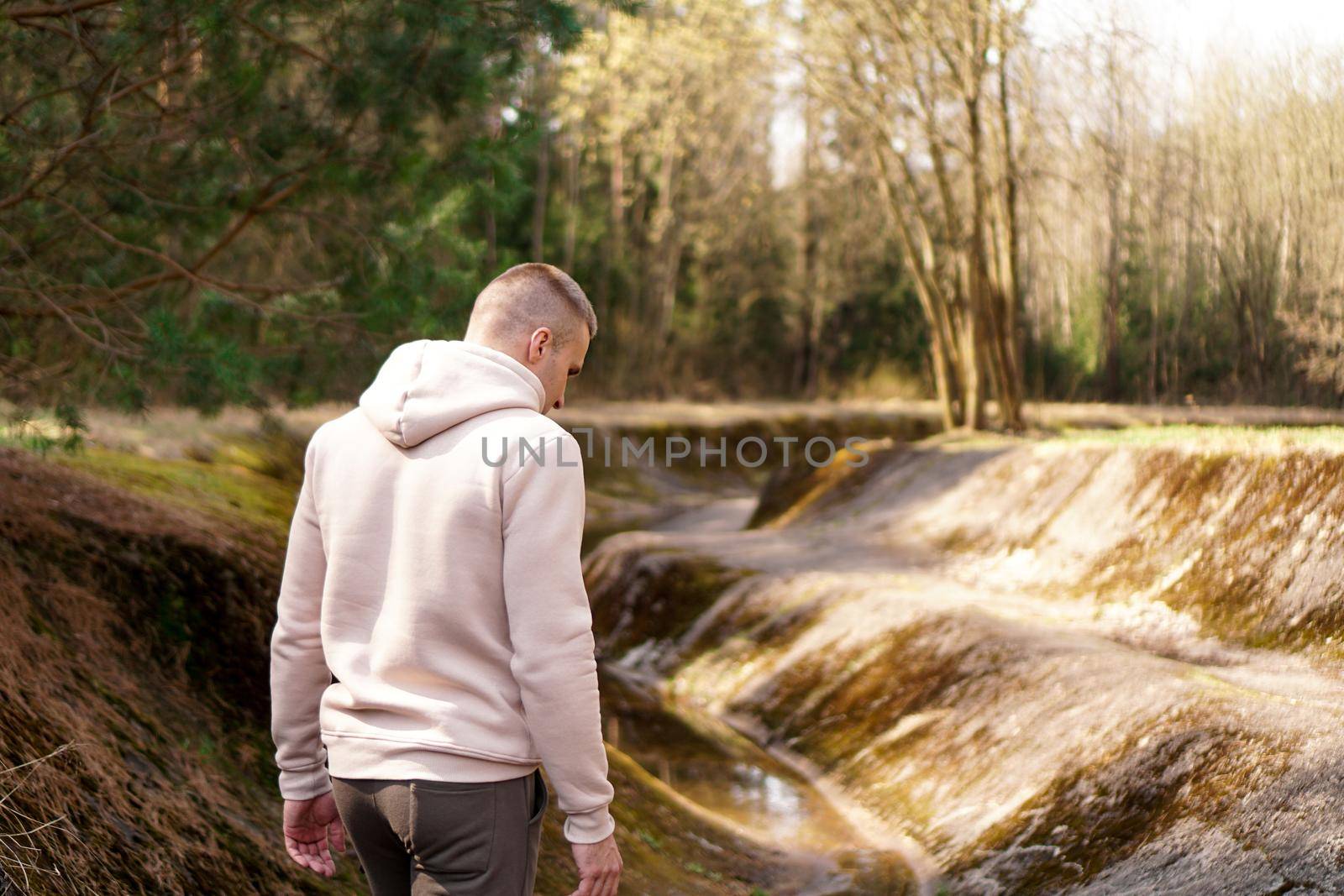 A man walks through the woods next to a rowing canal or mountain river. Picturesque places. The man's back. The concept of tourism and walking in nature