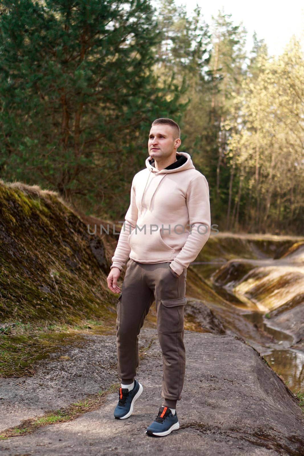 A young man in a comfortable suit walks through the forest by the river. Hiking and outdoor recreation concept