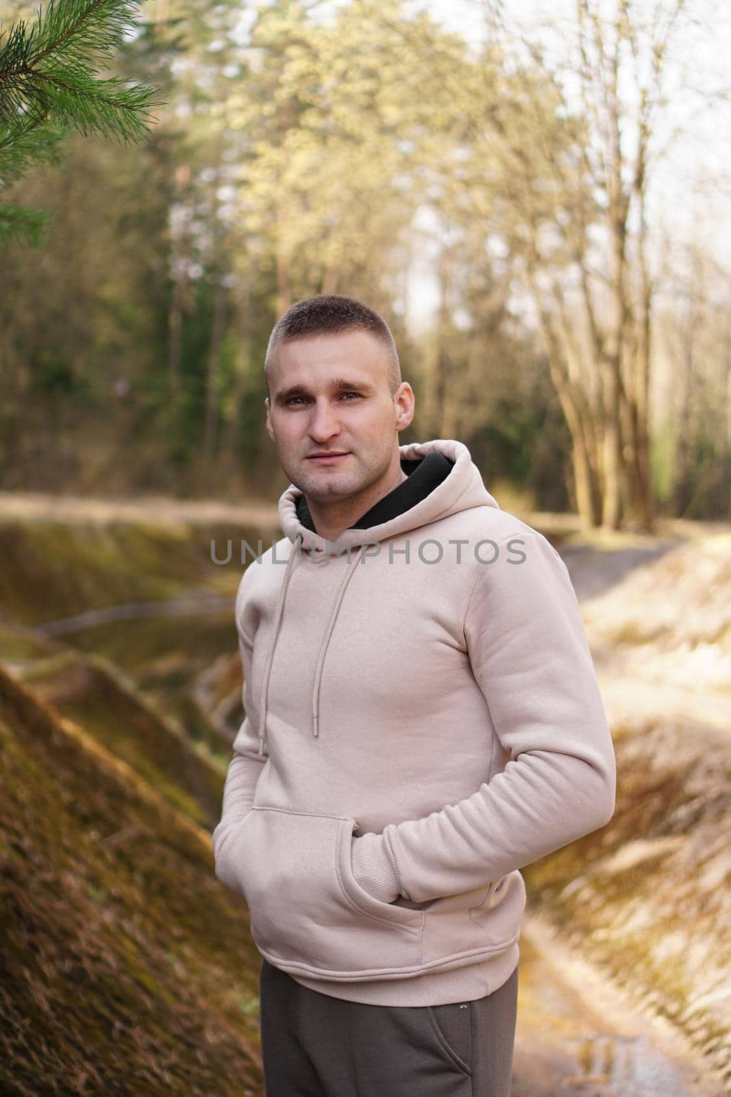 A young man in a comfortable suit walks through the forest by the river. by natali_brill