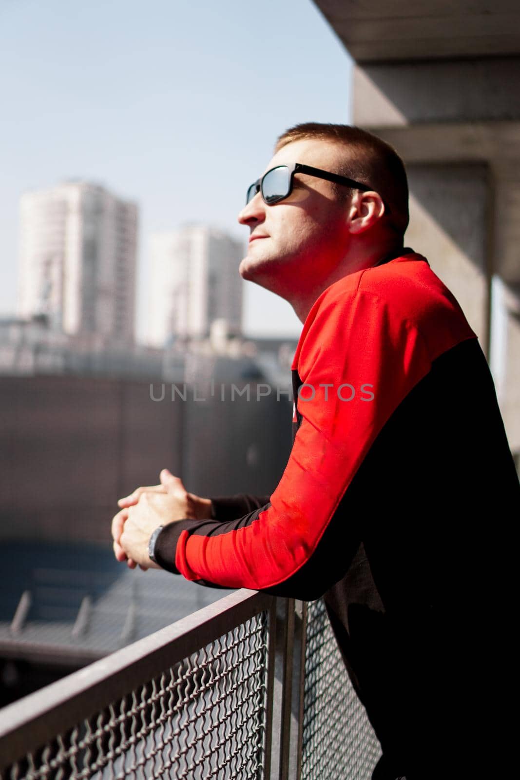 Young man in sports uniform in the parking lot. City view on a sunny day