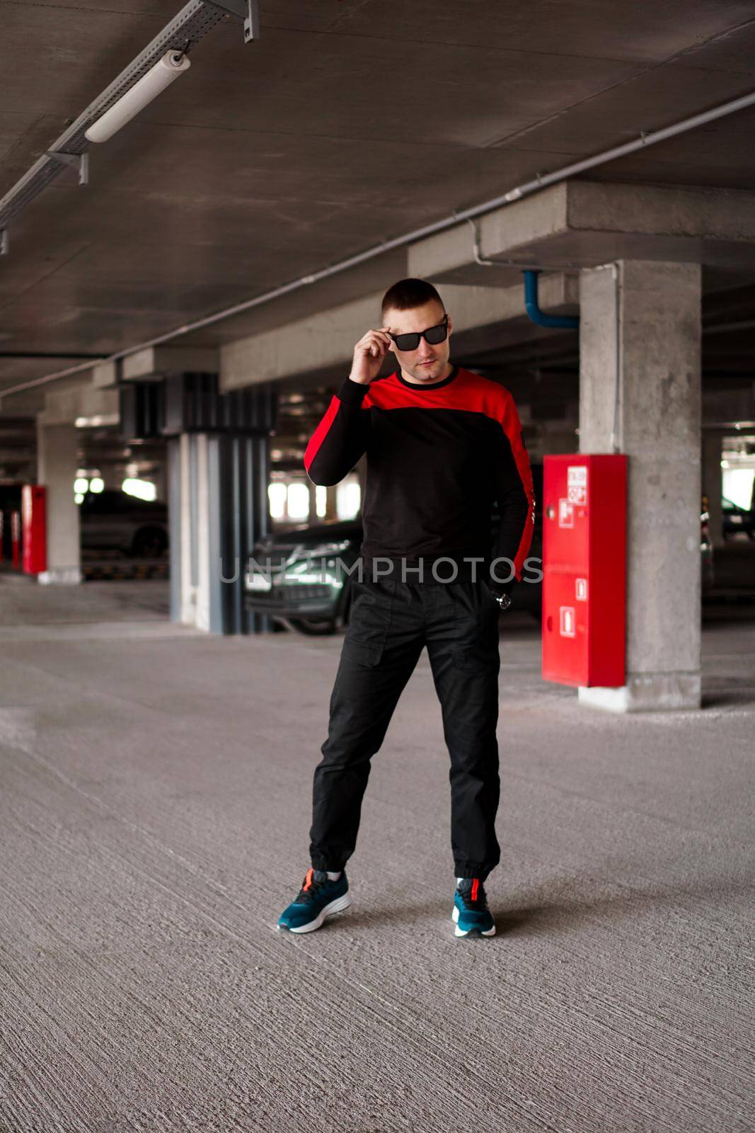 A young man in a sports uniform in sunglasses in an underground parking lot.