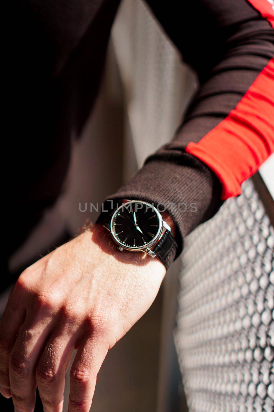 A man's hand in comfortable sportswear and an expensive watch on his wrist. Vertical photo.